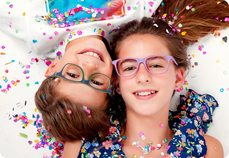 Kids eyewear campaign — two children with glasses and confetti on white.